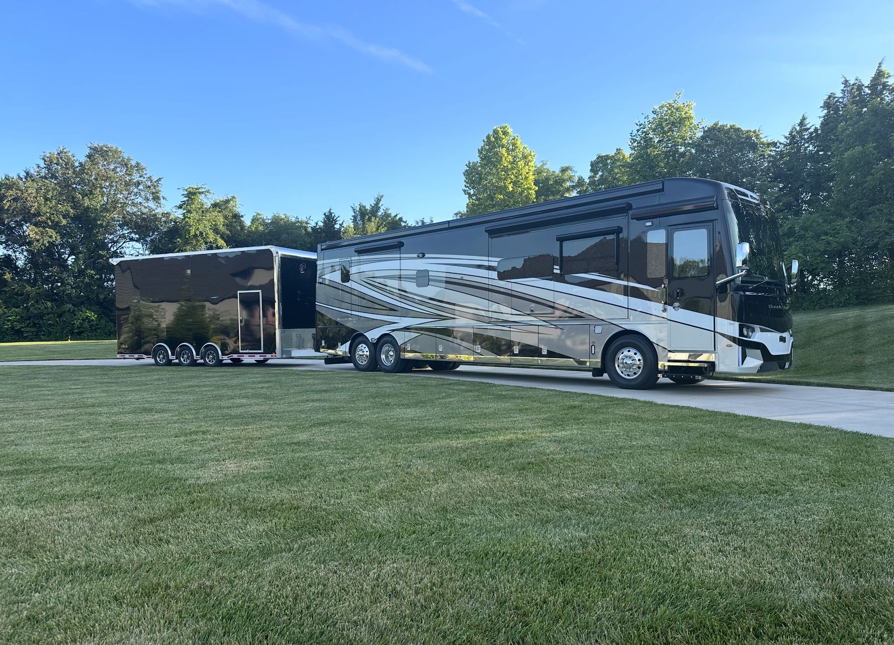 Luxury Newmar Dutch Star motorhome with an enclosed inTech stacker trailer on a manicured drive